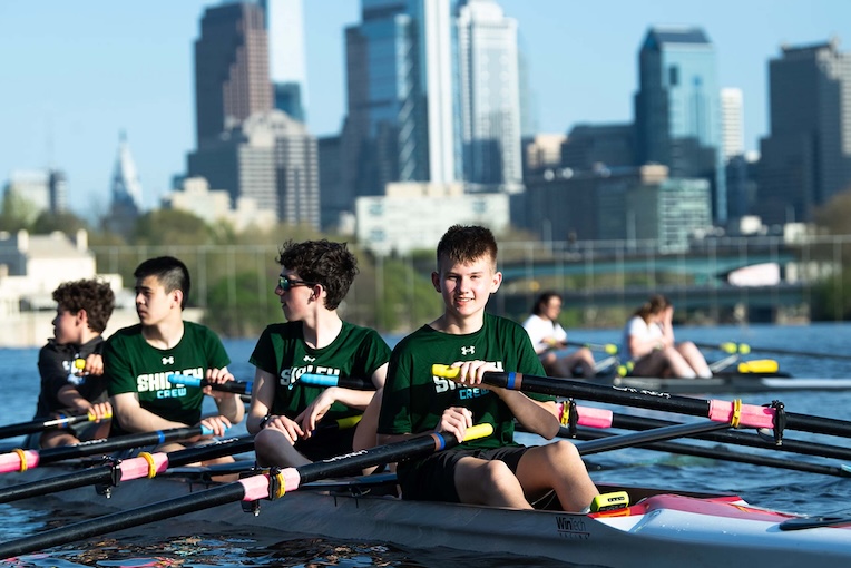 kids learning to row  on a river competitively at camp
