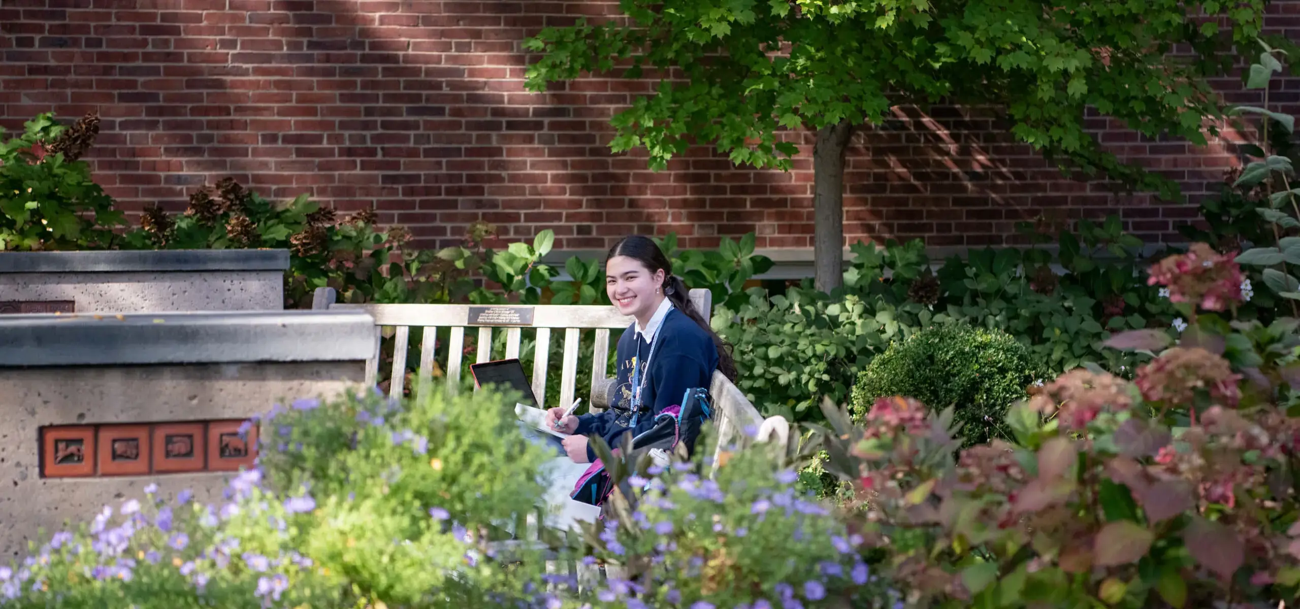 Girl in garden smiling while studying