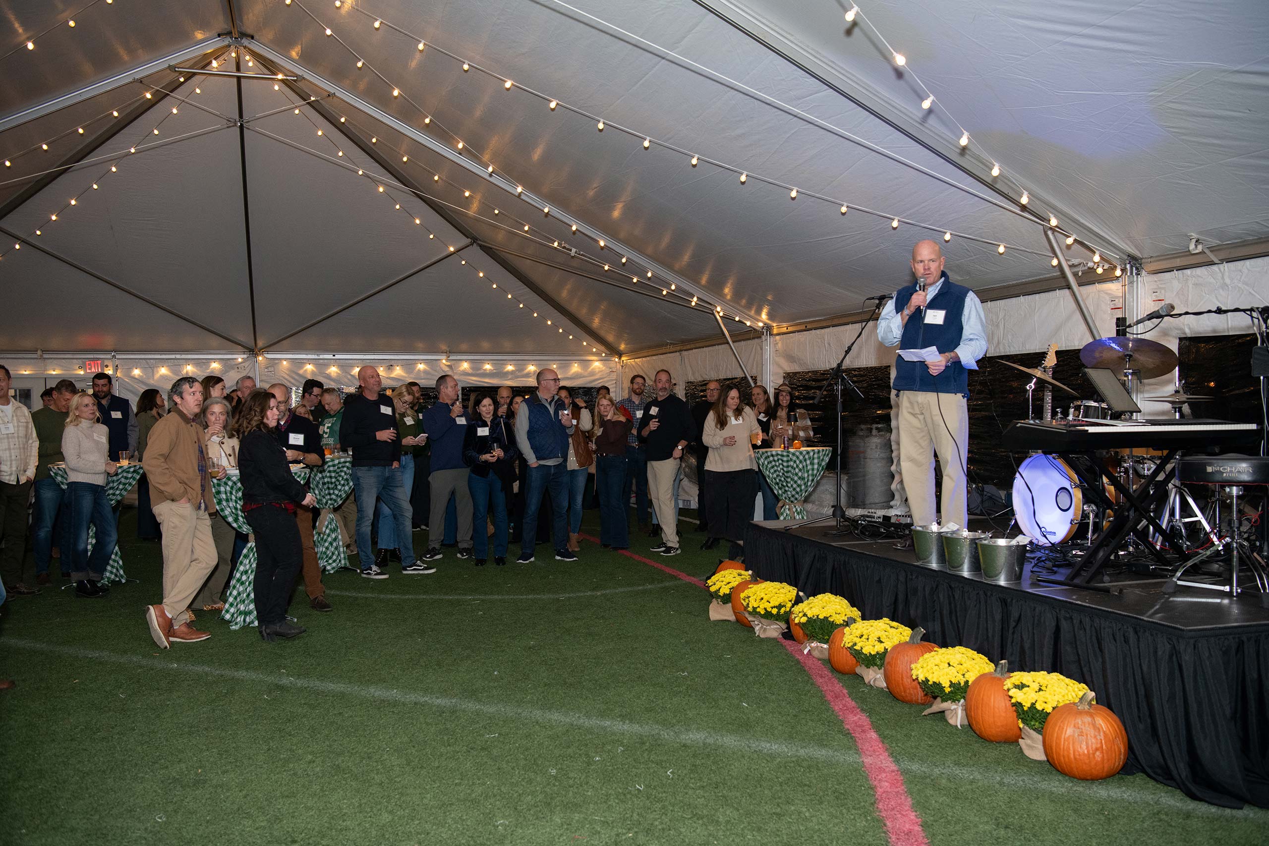 fall themed event under a tent, speaker addressing a crowd
