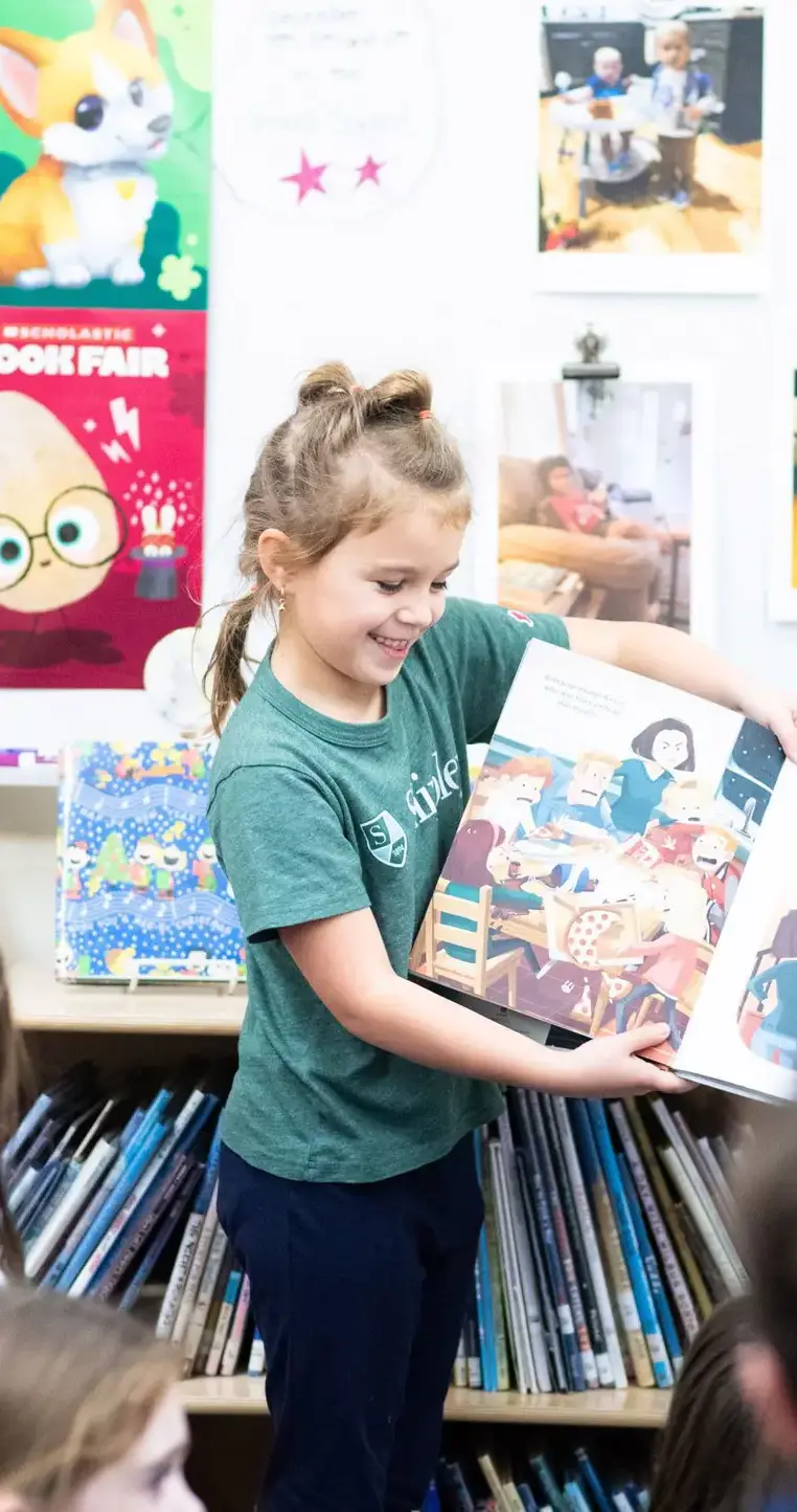 Student reading book to classmates in library