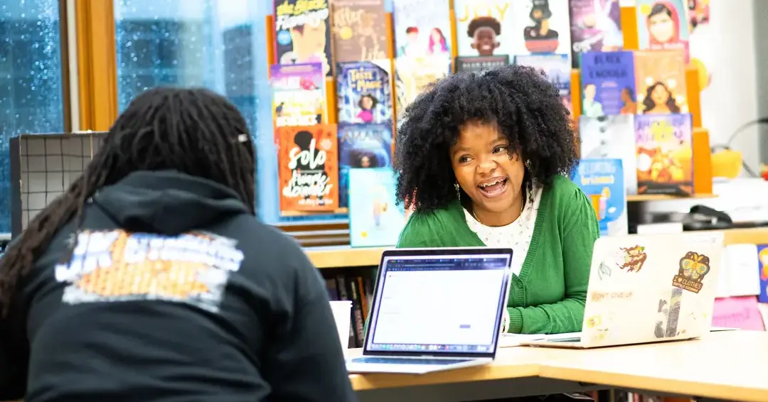 Students doing classwork on laptops and laughing together