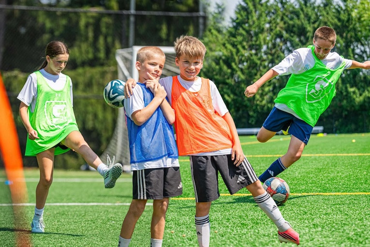 children in pinnies playing soccer on turf field