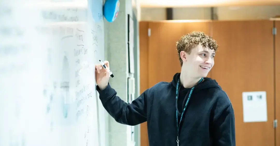 Student taking notes on whiteboard