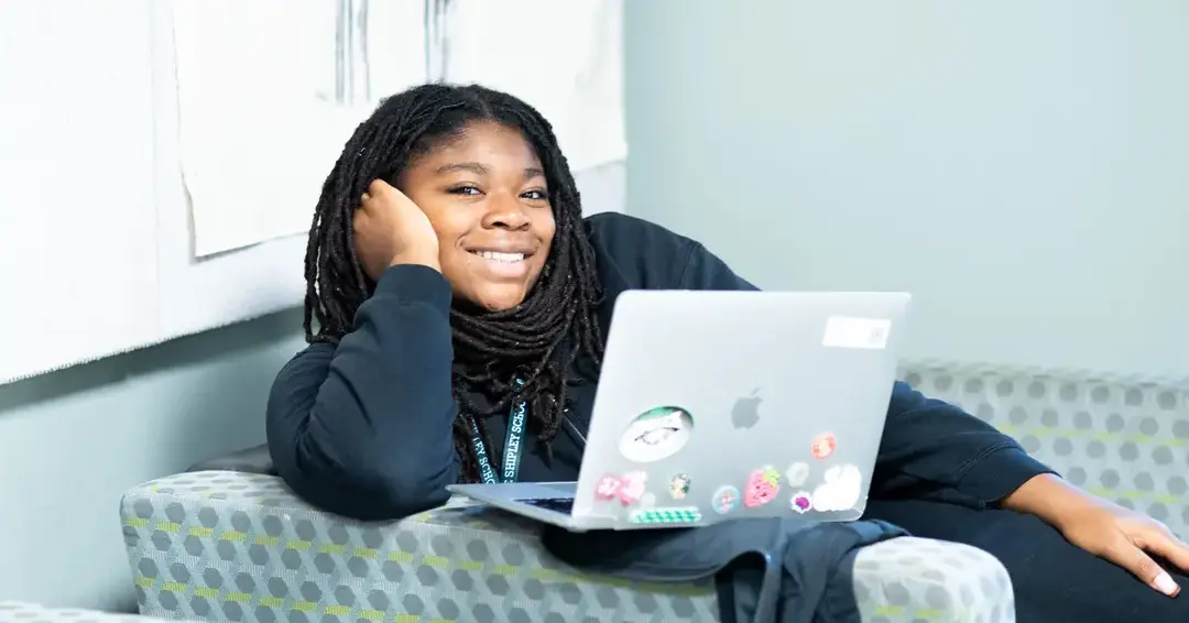 Upper school student smiling and doing school work on laptop