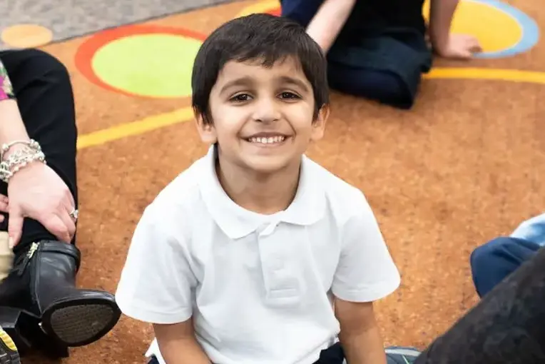 Student smiling and listening to teacher read book