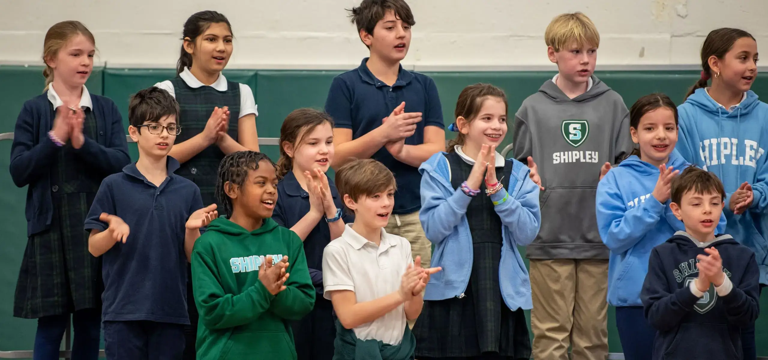 Students clapping and smiling during assembly